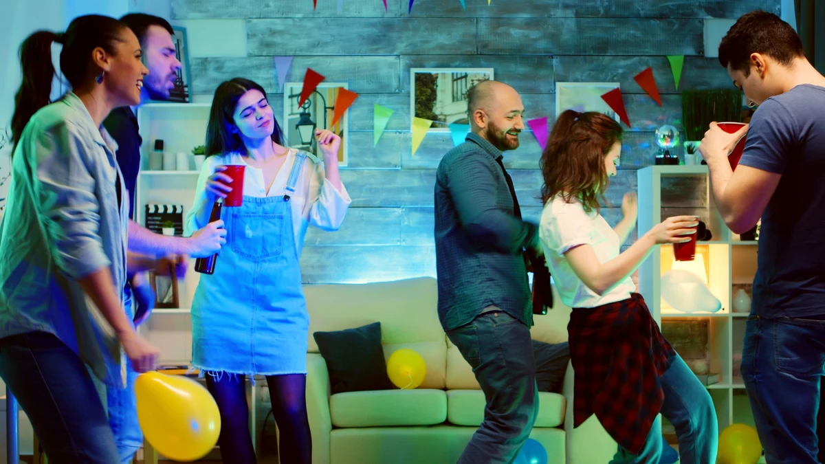 bald-attractive-young-man-smiling-while-dancing-party-with-his-friends-wild-college-party-with-neon-lights-disco-ball