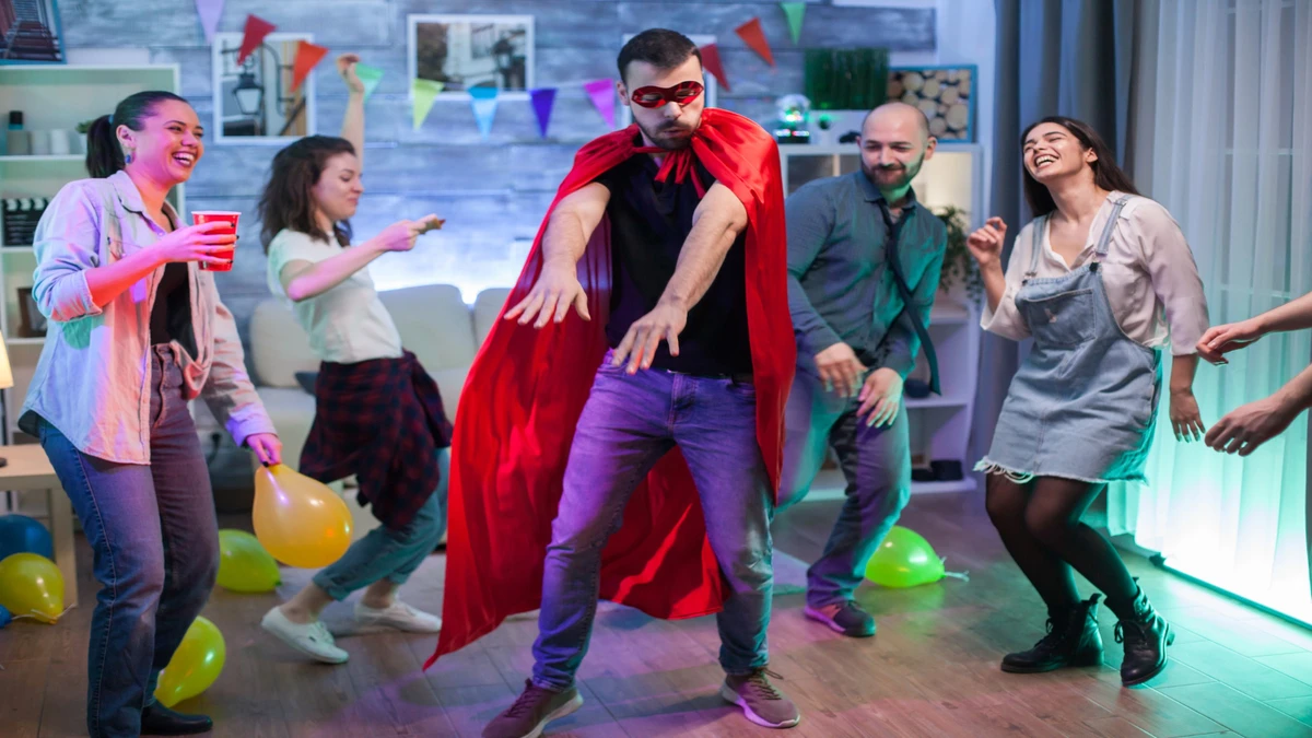 Cheerful man superhero costume showing his dance moves friends party